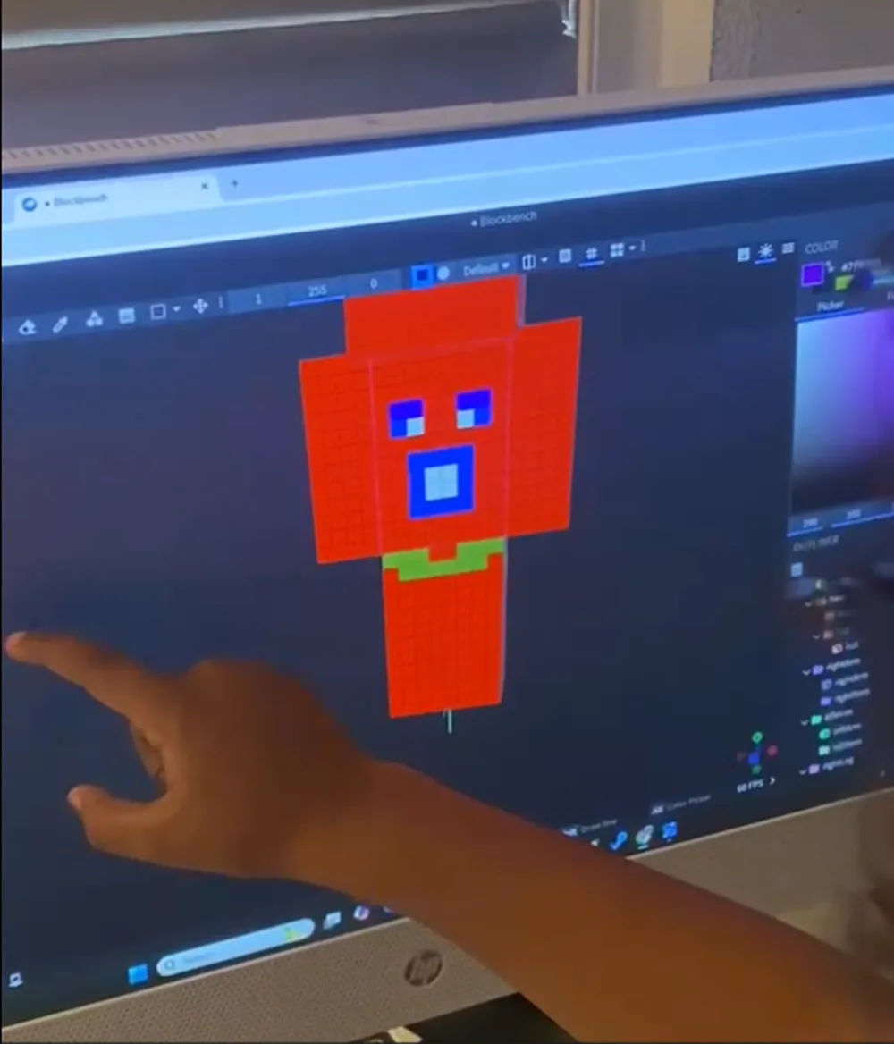 A child pointing at a custom red pixel-art character he modeled in Blockbench